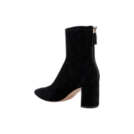 The Salome Stretch Suede Boot is a black ankle boot with a mid-high block heel, shown in side view. This boot features a pointed toe and a visible back zipper, all set against a plain white background.