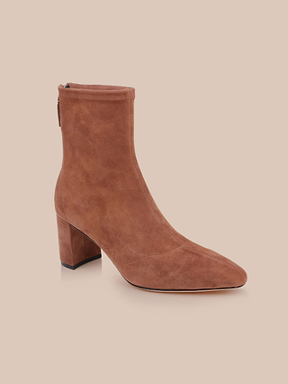 The Salome Stretch Suede Boot, featuring a pointed toe and a fashionable block heel in brown suede, is displayed on a light beige background.