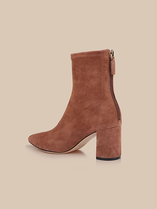 The Salome Stretch Suede Boot is a sophisticated tan ankle boot featuring a high block heel, pointed toe, and convenient back zipper, all displayed against a light beige background.