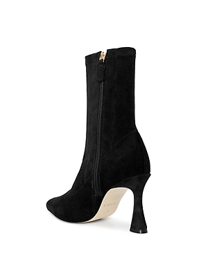 The Severine Stretch-Suede Boot, shown in black with a pointed toe, side zipper, and flared heel, is displayed from a rear side angle against a white background.