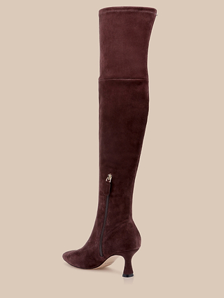 The Clarin Over-the-Knee Boot, crafted in mahogany brown suede with a pointed toe, side zipper, and a short, curved kitten heel, is displayed on a beige background.