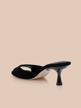 The Arleen Kitten-Heel Mule is displayed from the back against a beige background, showcasing its black suede open-toe design. This comfortable women’s shoe features a slender, slightly curved kitten heel with the insole subtly visible.