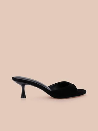 The Arleen Kitten-Heel Mule is a comfortable women’s shoe in black suede, featuring an open toe and a low, curved kitten heel with a simple, elegant design, displayed on a beige background.