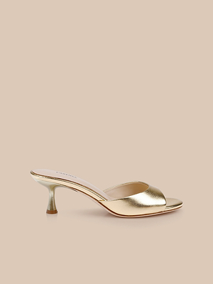 The Arleen Kitten-Heel Mule, crafted in gold leather with an open toe and a comfortable kitten heel, is shown on a beige background.