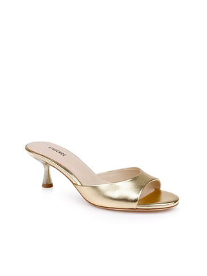 The Arleen Kitten-Heel Mule is a gold leather slip-on with an open toe and minimalist design, offering a comfortable lift from its low kitten heel. Elegantly showcased on a white background.