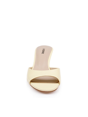 A front view of the Arleen Kitten-Heel Mule, a single beige leather open-toe slide sandal featuring a low kitten heel and wide front strap, displayed on a white background.