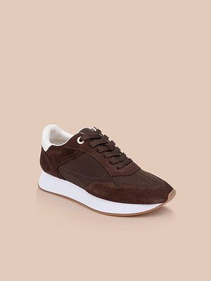 The Deepa Platform Sneaker, shown at an angle on a beige background, features chocolate suede and fabric with white accents, a thick white sole, and a memory foam insole.