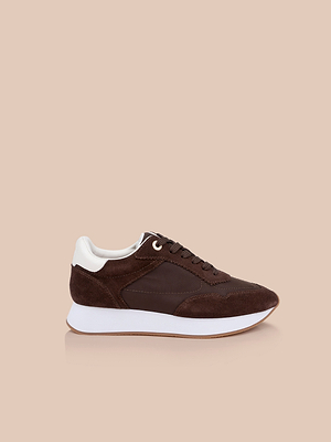 The Deepa Platform Sneaker features chocolate suede and leather with white heel accents, a chunky white sole, and memory foam insole, shown against a plain beige background.