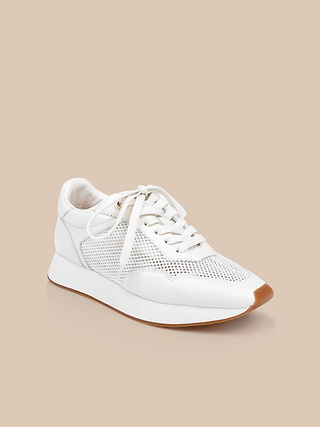 The Deepa Platform Sneaker showcases white leather with mesh panels and white laces, complemented by a light brown sole and a supportive memory foam insole, presented against a beige background.