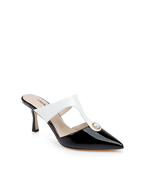 The Bayonne Mule is a black and white leather pointed-toe mule with a mid-height heel, featuring a cut-out white strap across the top and a circular jeweled accent.