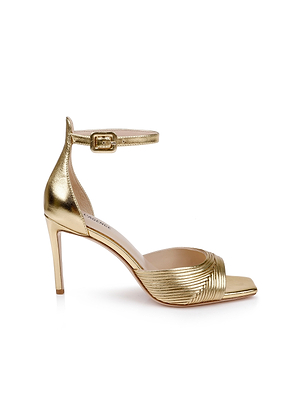 The Cici Stiletto Sandal is a gold metallic Nappa leather high-heeled sandal with a stiletto heel, ankle strap buckle, open toe, and textured front strap, displayed in side profile against a white background.