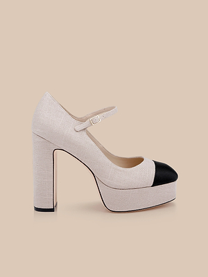 The Lilles Platform Pump is a beige Mary Jane with a block heel, platform sole, black rounded toe cap, and single buckle strap across the instep, shown on a beige background.