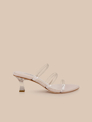 The Ludovica Kitten-Heel Sandal features sleek clear vinyl straps, a low clear acrylic heel, and a nude sole, shown against a light beige background.