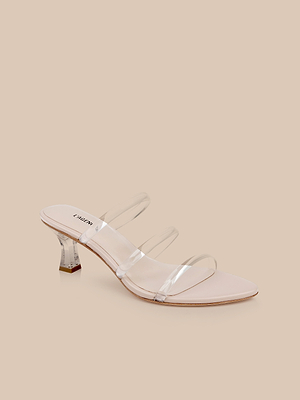 The Ludovica Kitten-Heel Sandal features a low, clear acrylic heel and three transparent vinyl bands over a nude footbed, shown against a beige background.