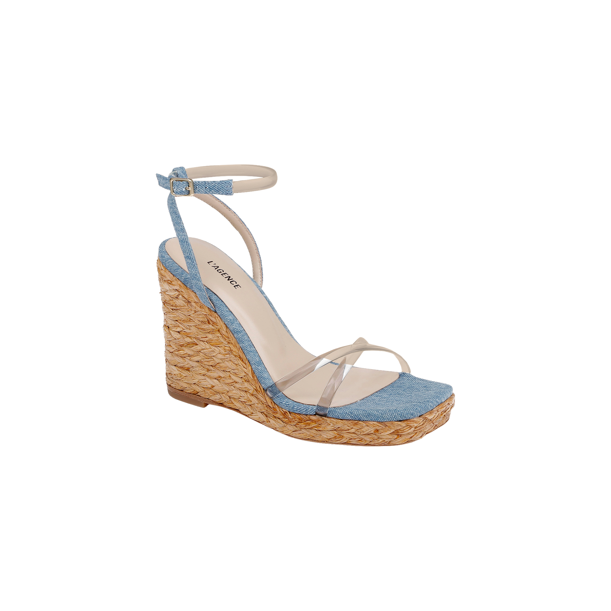 The Malone Wedge Espadrille is a bohemian-style wedge sandal showcasing a woven raffia heel, light blue fabric across the toe, clear straps over the foot, and a light ankle strap with buckle closure. Its cushioned beige insole provides comfort and is finished with a brand label.