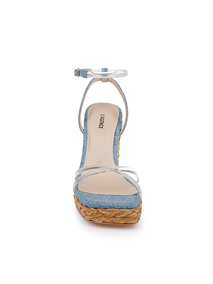 The Malone Wedge Espadrille is a women’s sandal featuring a blue denim upper, clear toe straps, tan footbed, ankle strap, and woven raffia wedge platform sole, displayed from the front against a white background.
