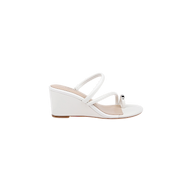 The Maritza Wedge Sandal is a white wedge sandal with two slim straps and a decorative silver bead near the toe. It features an open toe, a comfortable walkable wedge, and a low wooden sole.