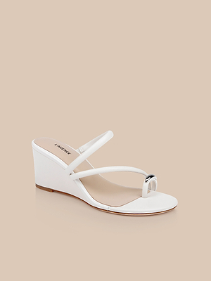The Maritza Wedge Sandal is a white walkable wedge with a leather upper, two slim straps—one crossing the foot and one wrapping the big toe—shown against a neutral beige background.