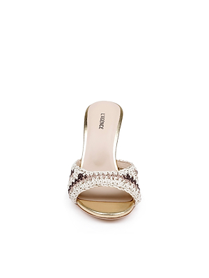 The Moyes Crochet Sandal is a single open-toe, high-heeled shoe with cream and brown woven straps, a sculpted heel, and a gold sole, displayed from the front on a white background.