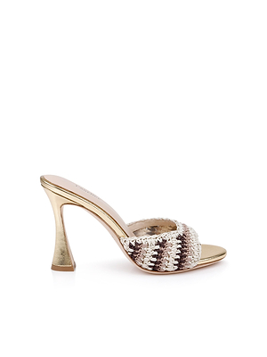 The Moyes Crochet Sandal is a gold high-heeled mule with a sculpted flared heel and open toe. Its wide woven strap blends metallic gold, brown, and cream tones for standout style.