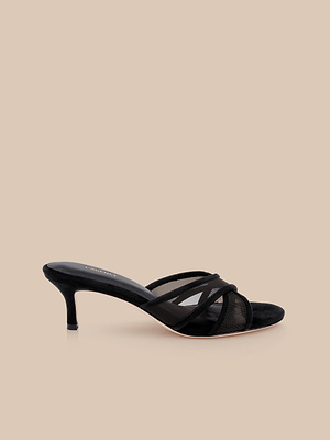 The Padua Mesh Sandal is a black heeled sandal with thin crisscross straps, a mid-height kitten heel, and a cushioned memory foam insole, shown on a beige background.