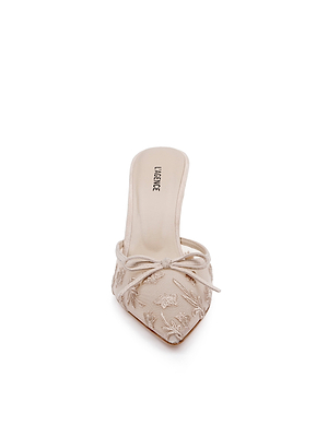 Front view of the Prasad Mesh Mule in beige, featuring a pointed toe, butterfly embroidery, a decorative bow on top, and an insole labeled LARROWE, all set against a plain white background.