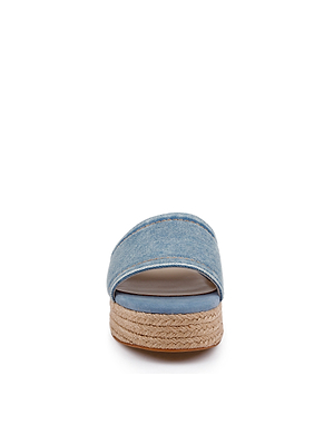 Front view of the Ramani Platform Espadrille, a blue denim slide sandal featuring a wide strap and thick woven jute platform sole, ideal for spring and summer, shown against a white background.
