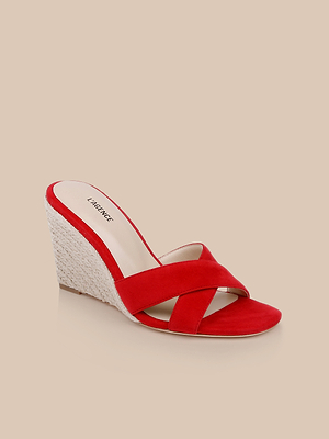 The Rosaline Wedge Espadrille features crisscross suede straps and a woven platform heel, making it an ideal womens summer sandal. Shown on a beige background.