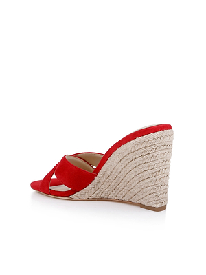 The Rosaline Wedge Espadrille is a red suede sandal featuring a criss-cross vamp and a high, textured espadrille wedge heel, shown against a white background.