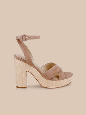 The Sandrine Platform Sandal in tan suede features wide toe straps, an adjustable buckle ankle strap, and a chunky raffia-wrapped wedge heel, shown on a beige background.
