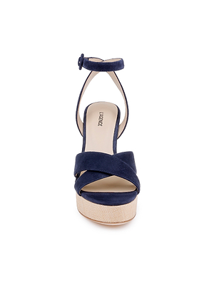Front view of the Sandrine Platform Sandal in navy suede, featuring open toes, crisscross straps, a raffia-wrapped wedge sole, ankle strap with round buckle, and a light tan insole.
