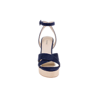 The Sandrine Platform Sandal is shown from the front, featuring navy suede crisscross straps, an ankle strap with a buckle, and a light tan sole elevated by a raffia-wrapped wedge, all set against a plain white background.