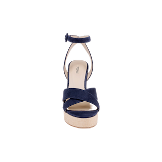 The Sandrine Platform Sandal is shown from the front, featuring navy suede crisscross straps, an ankle strap with a buckle, and a light tan sole elevated by a raffia-wrapped wedge, all set against a plain white background.