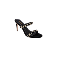 Introducing the Sarika Chain Sandal: a high-fashion sandal crafted in black suede, featuring two straps adorned with bold gold chain hardware. This elegant design is completed with an open toe and a slender stiletto heel.