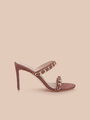 The Sarika Chain Sandal in dusty rose features a suede heel and two straps accented with gold chain hardware, shown against a solid beige background.
