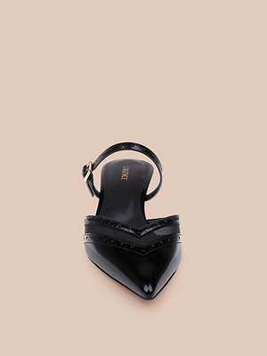 The Shelbie Kitten-Heel Mule, a black leather pointed-toe mule with slingback strap and gold buckle, is shown from above on a beige background.