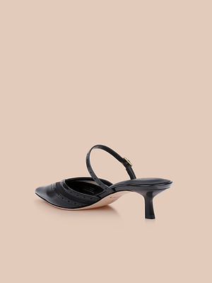 The Shelbie Kitten-Heel Mule, a black leather shoe with a pointed toe and cut-out detailing, is displayed against a plain beige background.