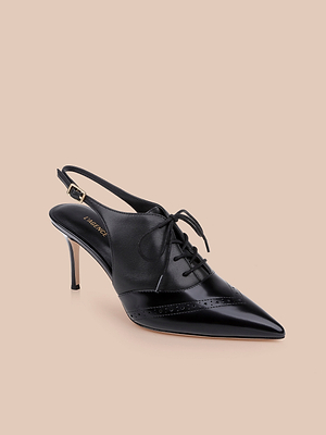 The Shreya Leather Slingback Pump features a black leather pointed toe, lace-up front, brogue details, and a thin oxford stiletto heel, shown against a beige background.