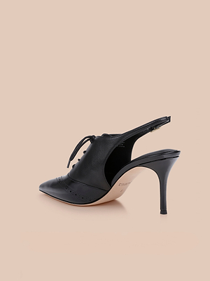 The Shreya Leather Slingback Pump is a black pointed-toe oxford stiletto with lace-up front and cut-out sides, shown on a beige background.