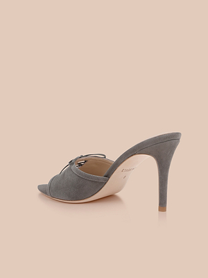 The Thames Suede Sandal, a single grey mule with a pointed toe, stiletto heel, and bow detail, is displayed on a light beige background at an angle revealing the side and back heel.