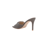 The Thames Suede Sandal is a chic gray high-heeled mule shoe featuring an open toe and a thin stiletto heel, shown from the side against a plain white background. This elegant grey suede sandal is perfect for formal occasions.