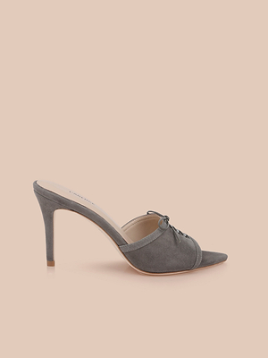 The Thames Suede Sandal is a gray high-heeled mule with a pointed toe, lace-up detail, stiletto heel, and suede-like finish, shown on a plain beige background.