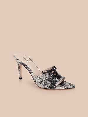 The Thames Sandal is a high-heeled, open-toe mule with a black and white marbled pattern, stiletto heel, and decorative bow on the upper, shown on a neutral beige background.