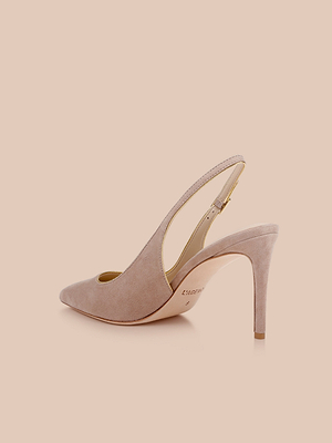 The Vichy Slingback Pump is shown in blush pink with a pointed toe, gold piping, and a slim high heel, set against a light beige background.