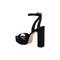 The Essie Platform Sandal is a black suede shoe featuring an ankle strap, a thick block heel, an open toe, and gold ring detail on the front strap, displayed on a white background.