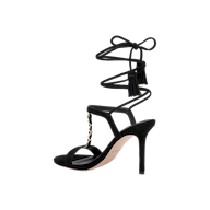 The Bond Suede Sandal is a black high-heeled shoe featuring an open toe, ankle wrap-around laces with tassel details, and a gold chain accent on the upper strappy heel.