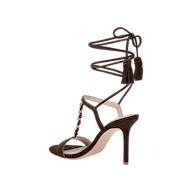 The Bond Suede Sandal is a dark brown single sandal with a strappy heel design, ankle wrap straps, tassel accents, gold studs along the front, and an open toe, shown against a plain white background.