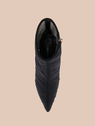 Top view of the Fulton Mesh Bootie—a black, textured stiletto bootie with a pointed toe and side zipper—displayed on a beige background.