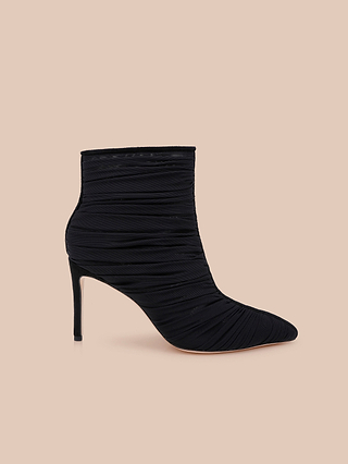 The Fulton Mesh Bootie, featuring a black pointed toe and ruched mesh design, is displayed on a beige background.