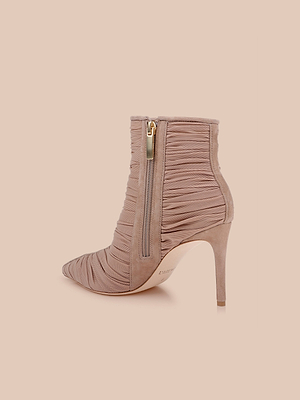 Le scarpe Fulton Mesh Bootie sono caratterizzate da un tessuto increspato rosa blush, da una punta appuntita e da una cerniera laterale dorata, elegantemente visualizzate su uno sfondo color pesca chiaro.